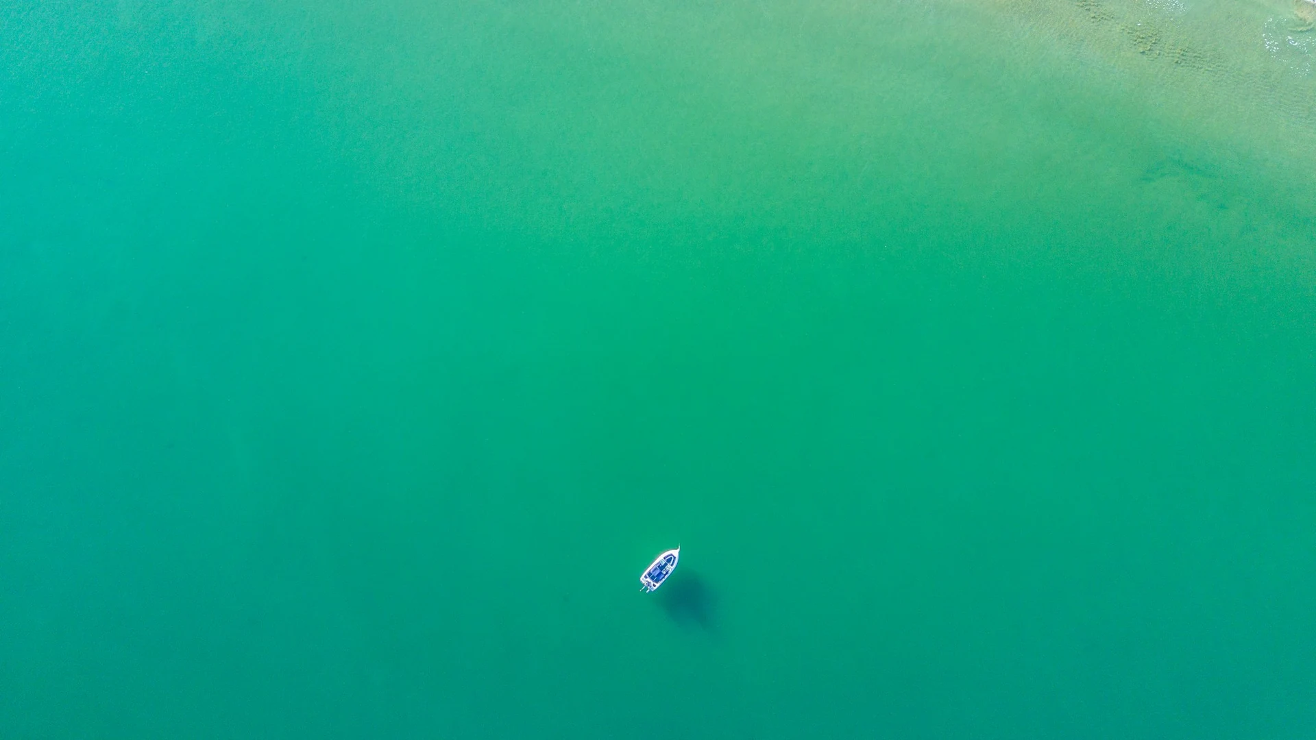 Aerial view of a lone boat on clear turquoise water