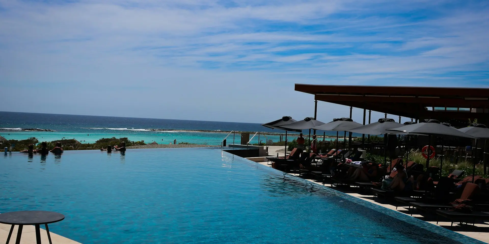 Infinity pool and sun loungers above a turquoise sea