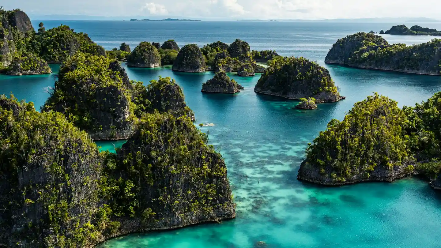 Jungle-covered karst islets in a turquoise lagoon in Raja Ampat