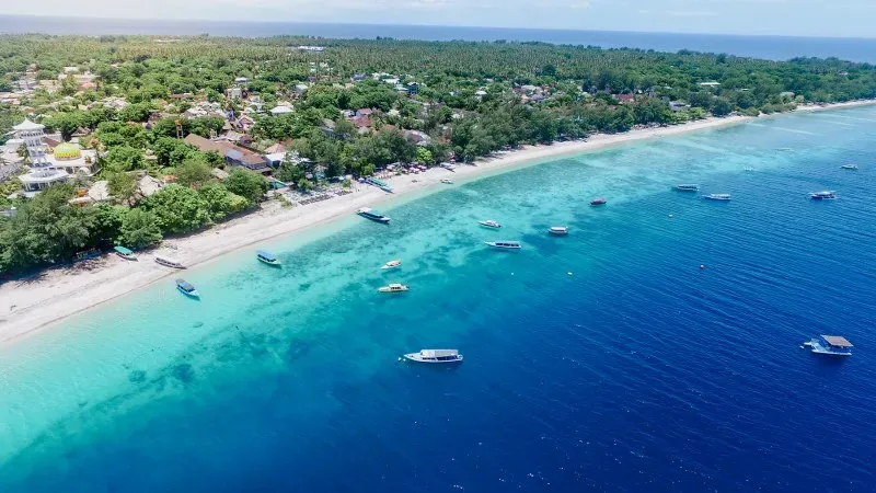 Aerial view of the Gili Trawangan coastline with boats moored over turquoise shallows